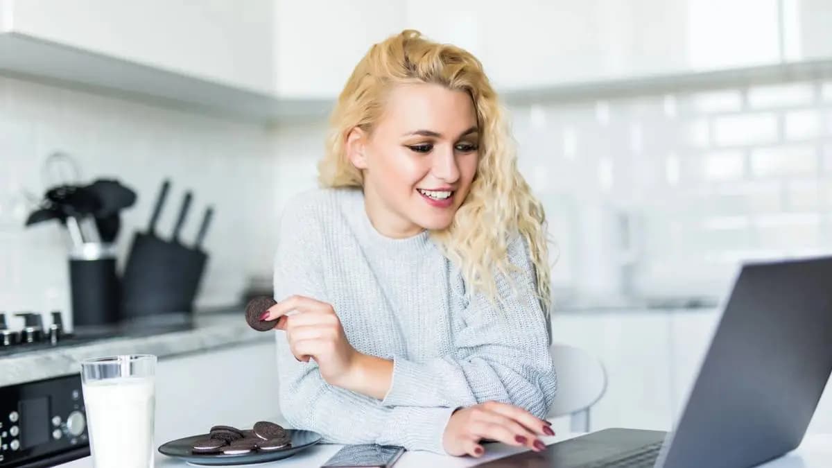 mladá žena se usmívá u laptopu, povídá si s AI