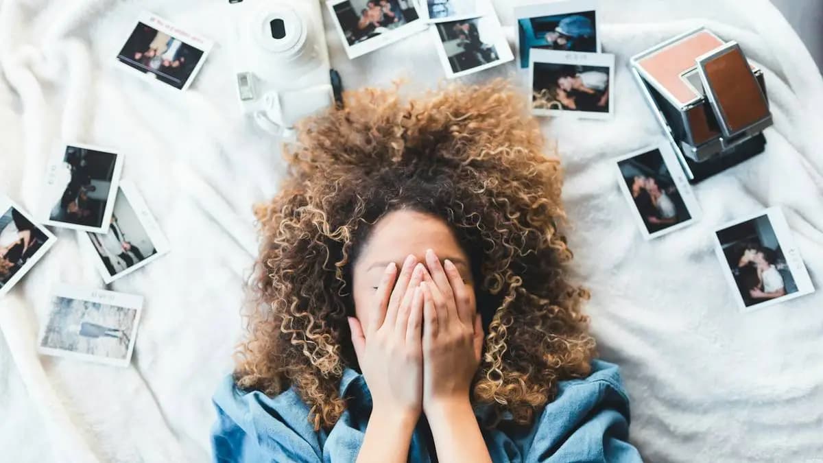 žena leží na posteli, kolem ní jsou fotky a instax žena leží na posteli, kolem ní jsou fotky a instax