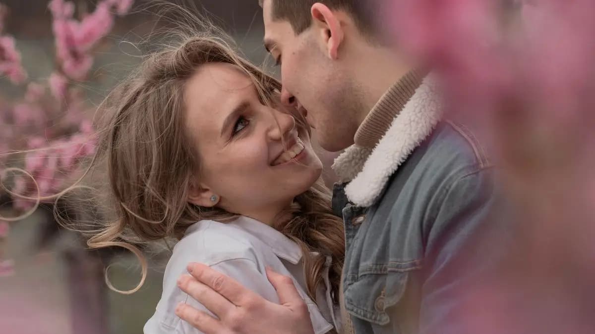 Zamilovaný pár v objetí za rozkvetlými větvemi stromu Zamilovaný pár v objetí za rozkvetlými větvemi stromu