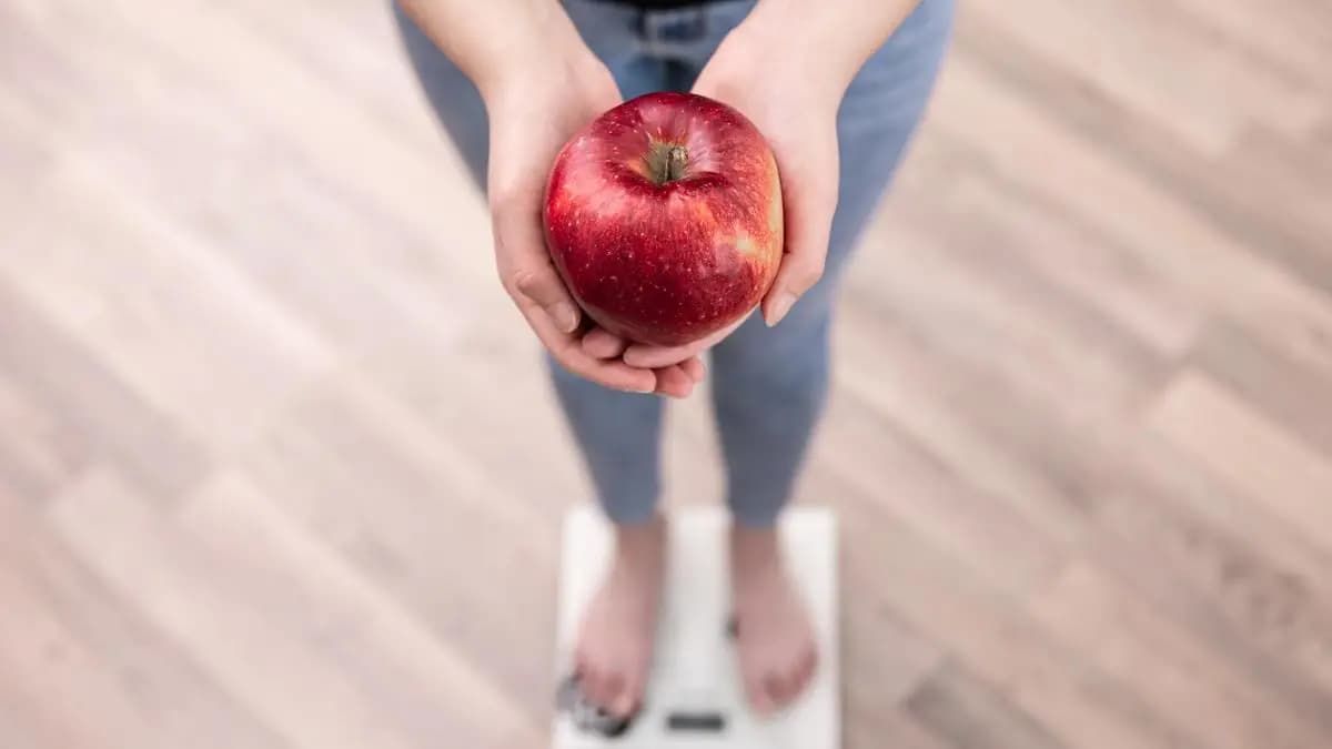 žena drží jablko v ruce a stojí na váze žena drží jablko v ruce a stojí na váze