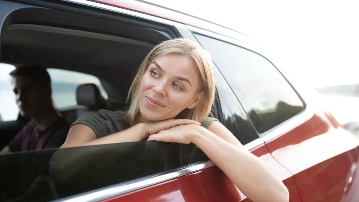 žena vzadu na sedačkách v autě, má hlavu a ruce z okénka a dívá se na provoz před sebou žena vzadu na sedačkách v autě, má hlavu a ruce z okénka a dívá se na provoz před sebou