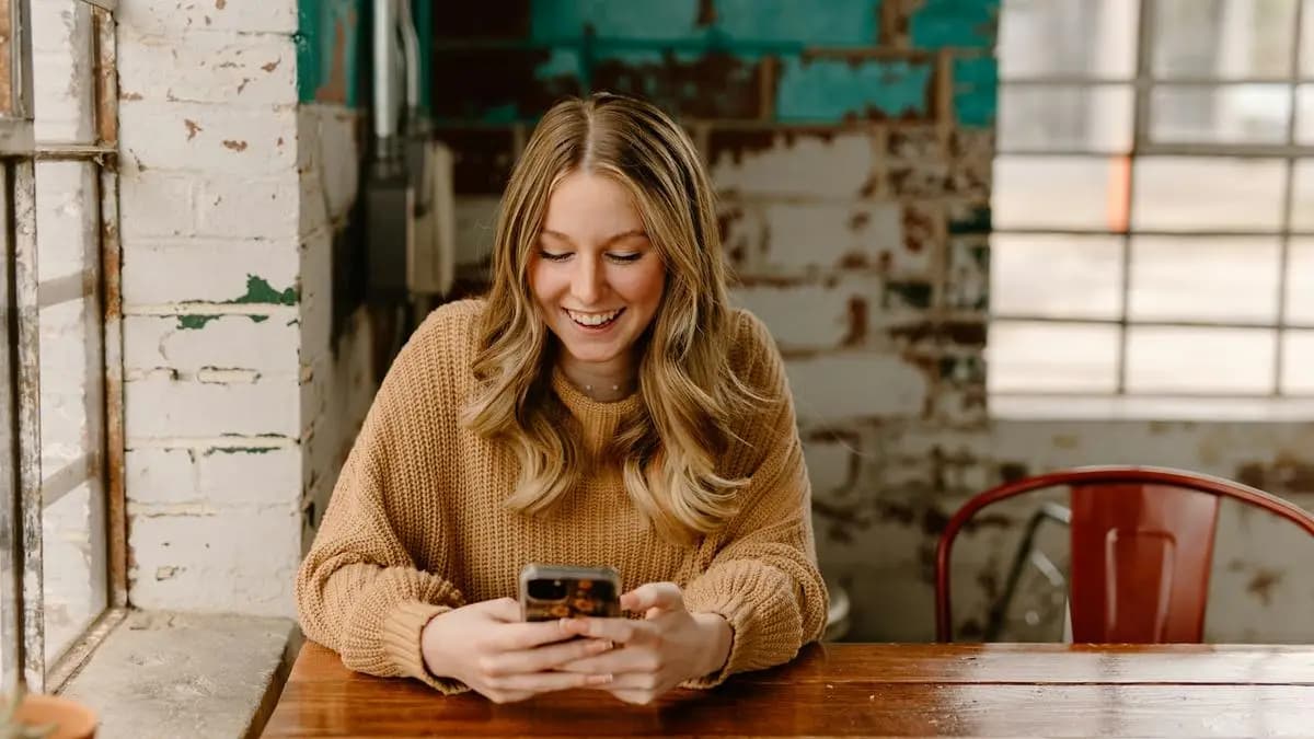 žena se usmívá na telefon, něco tam čte v kavárně žena se usmívá na telefon, něco tam čte v kavárně