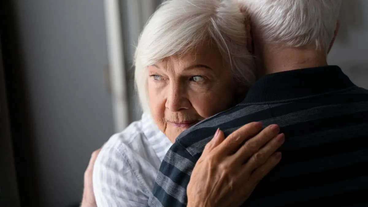 pár seniorů se objímá, žena se dívá smutně směrem pryč pár seniorů se objímá, žena se dívá smutně směrem pryč