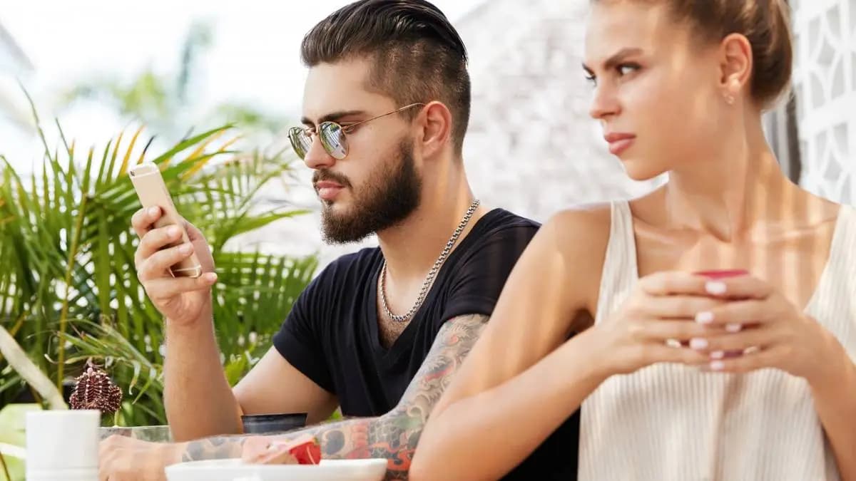 Naštvaná žena se odvrací od partnera, který se dívá do mobilu Naštvaná žena se odvrací od partnera, který se dívá do mobilu