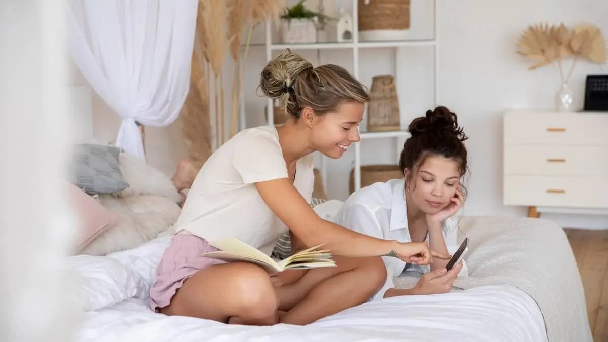 dvě dívky na posteli, jedna čte a ta druhá něco dělá na mobilu dvě dívky na posteli, jedna čte a ta druhá něco dělá na mobilu