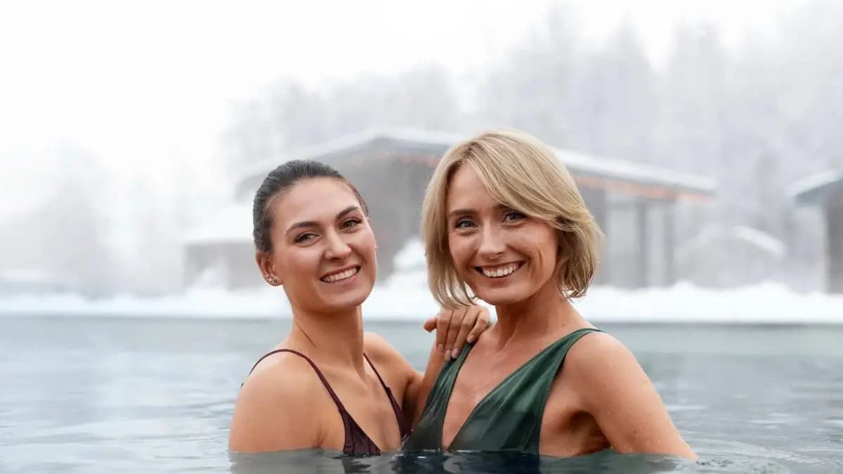 Dvě usměvavé ženy v teplém venkovním bazénu za sněžení. Dvě usměvavé ženy v teplém venkovním bazénu za sněžení.