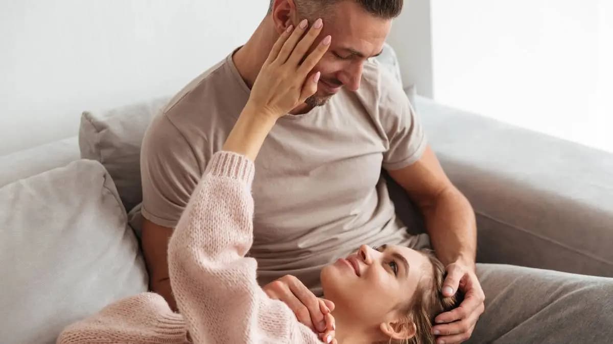 Žena leží muži v klíně a něžně ho hladí po tváři Žena leží muži v klíně a něžně ho hladí po tváři